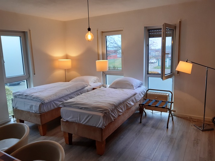 Zwei Betten im Schlafzimmer mit Lampen und einem geöffneten Fenster