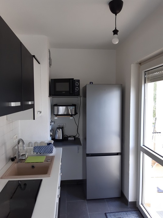 Küche mit Kühlschrank, Toaster, Mikrowelle und Wasserkocher